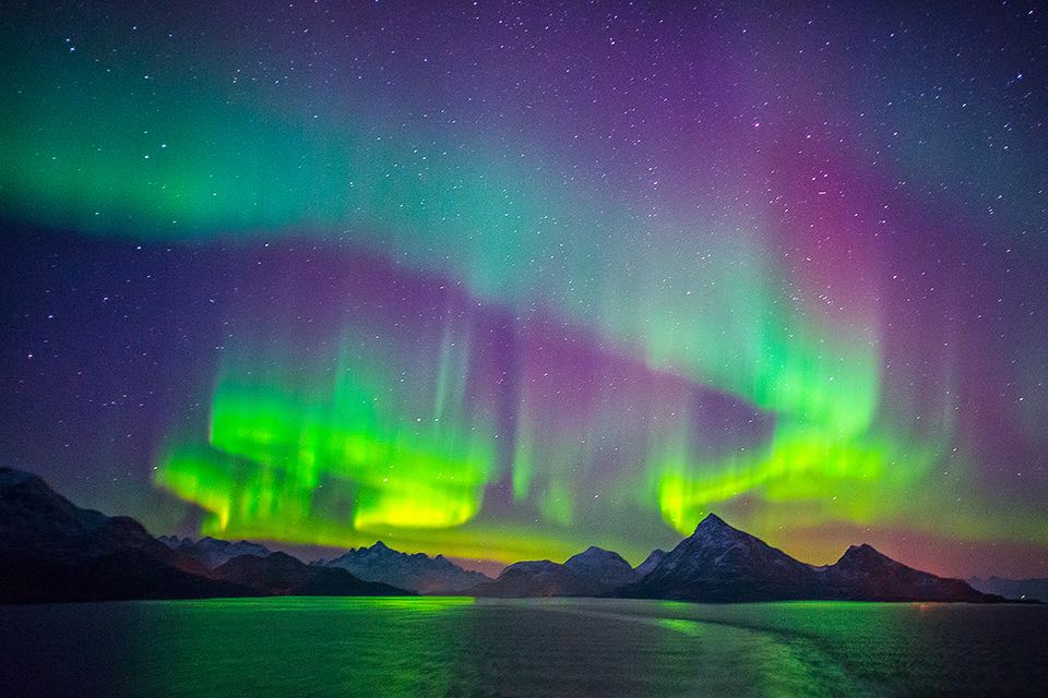 starkes und intensiv leuchtendes rotes und gruenes Polarlicht in Norwegen