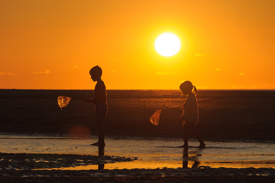 Spielende Kinder im Sonnenuntergang am Strand