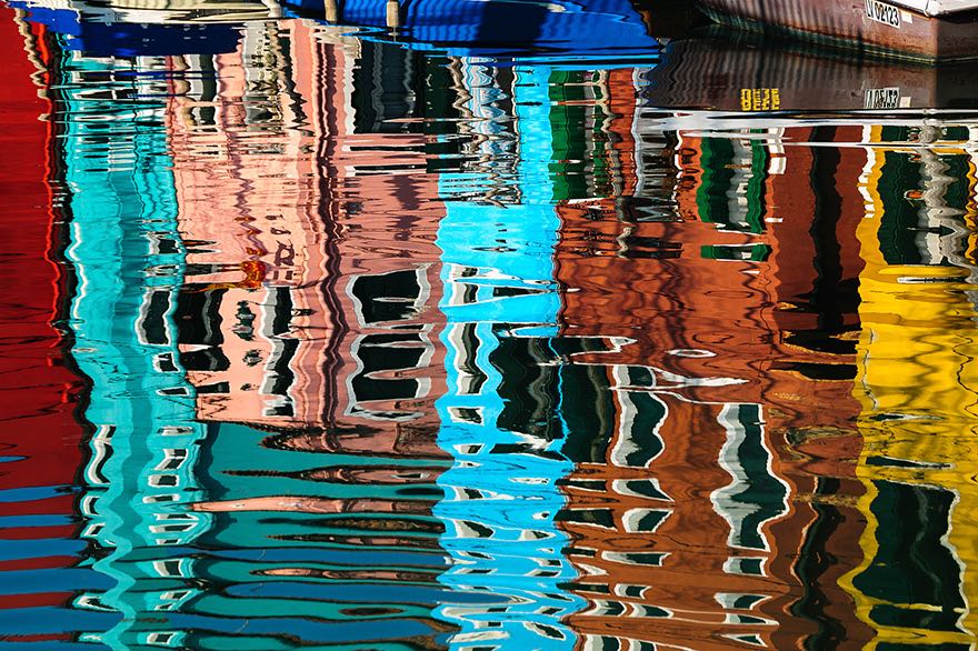 Wasserspiegelungen der bunten Haeuser auf Burano in Italien